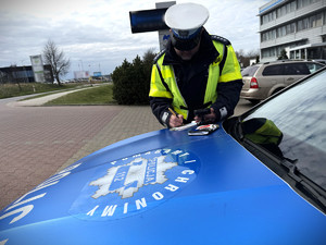Policjant pisze w notatniku służbowym.