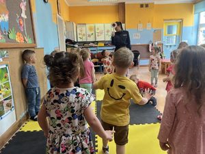 Policjantka prowadzi zajęcia z przedszkolakami.