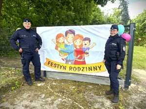 Policjant i policjantka przy banerze z napisem festyn rodzinny.