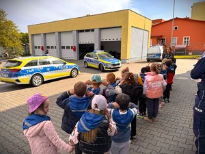 Przedszkolaki na placu komendy oglądają radiowozy.