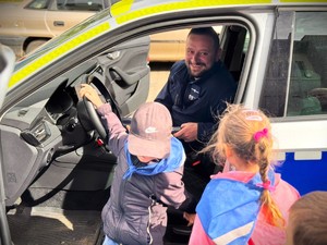 Policjant pokazuje przedszkolakom wnętrze radiowozu.