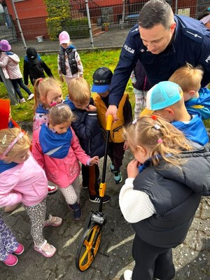 Policjant pokazuje dzieciom koło do mierzenia odległości.