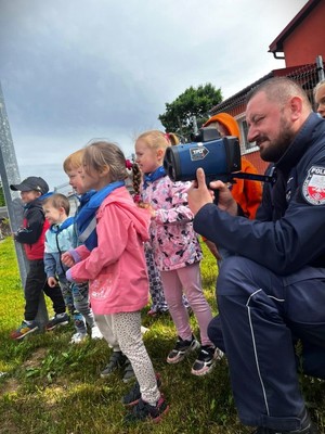 Policjant pokazuje dzieciom działania laserowego miernika prędkości.