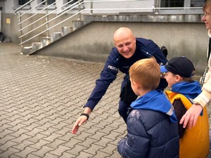 Policjant wraz przedszkolakami na placu jednostki.