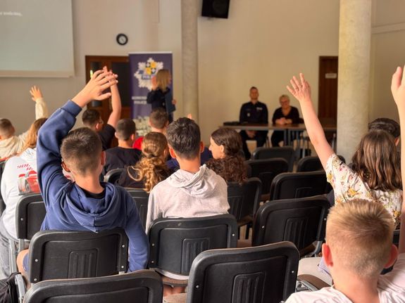 Policjantka prowadzi debatę społeczną dla młodzieży.