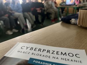Poradnik na temat cyberzagrożeń. W tle uczniowie.