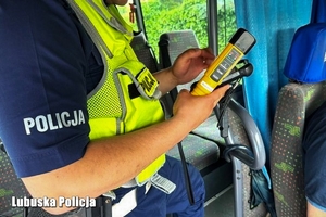 Policjant kontroluje trzeźwość kierowcy autokaru.