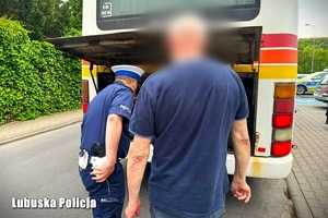 Policjant sprawdza stan techniczny autokaru w obecności kierowcy.