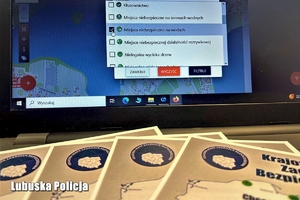 Ulotki na temat Krajowej Mapy Zagrożeń Bezpieczeństwa oraz laptop z uruchomioną aplikacją.