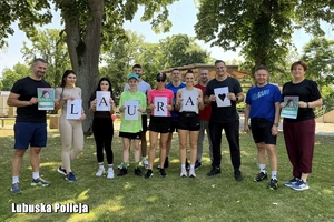 Policjanci i pracownicy cywilni ubrani na sportowo trzymają w dłoniach napis Laura oraz informacje o zbiórce na rzecz dziewczynki.