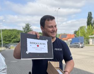 Policjant z pracą plastyczną od dzieci.