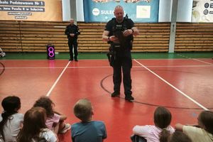 Dzielnicowi przeprowadzają spotkanie edukacyjne dla uczniów na sali gimnastycznej.