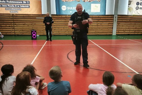 Dzielnicowi przeprowadzają spotkanie edukacyjne dla uczniów na sali gimnastycznej.