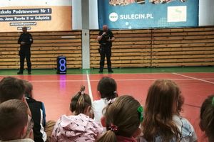 Dzielnicowi przeprowadzają spotkanie edukacyjne dla uczniów na sali gimnastycznej.