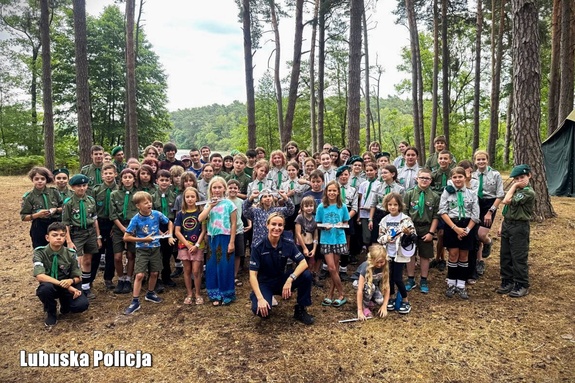Policjantka pozuje do wspólnego zdjęcia z uczestnikami obozu harcerskiego.