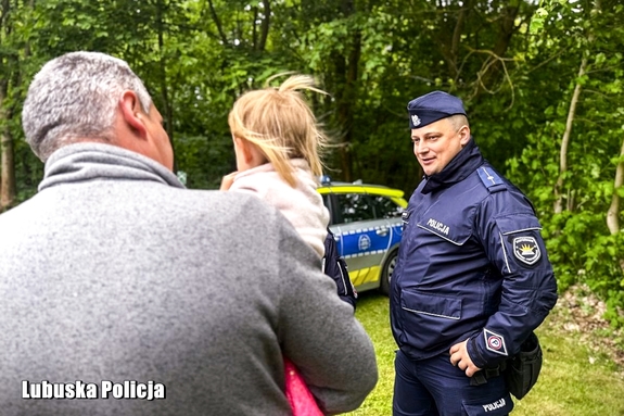 Policjant rozmawia z mężczyzną trzymającym na rękach małą dziewczynkę.