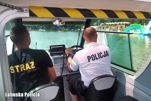 Policjant i strażak patrolują jezioro łodzią.