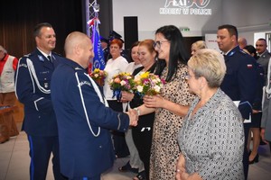 Sulęcińscy komendanci wręczają kwiaty policjantkom i paniom pracującym w komendzie.