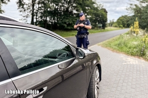 Policjant spisuje tablice rejestracyjne pojazdu podczas kontroli drogowej.