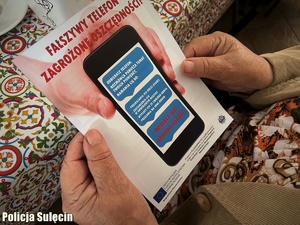 Seniorka trzyma w dłoniach ulotkę informacyjną.