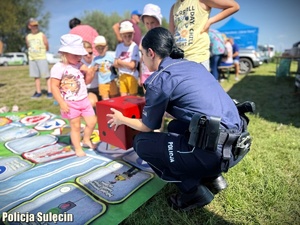 Policjantka podaje dzieciom kostkę do gry.