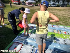 Policjantka tłumaczy dzieciom zasady wielkoformatowej gry.