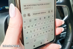 Kobieta trzyma w dłoni telefon komórkowy.
