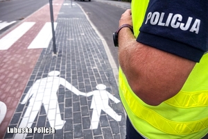 Policjant sprawdza stan oznakowania poziomego.
