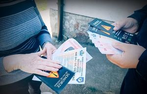 Policjant przekazuje seniorce materiały edukacyjne na temat oszustw.
