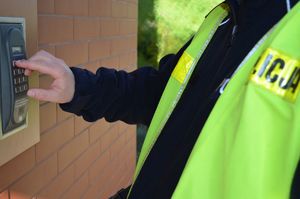 Policjant naciska przycisk domofonu.