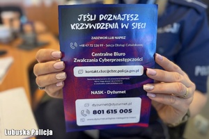 Policjantka trzyma w dłoniach plakat o tematyce przeciwdziałania hejtowi.