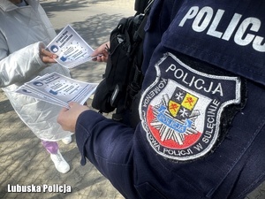 Dzielnicowy wręcza kobiecie ulotkę promującą Krajową Mapę Zagrożeń Bezpieczeństwa.