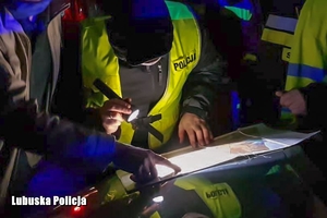 Policjanci czytają mapę podczas poszukiwań osoby.