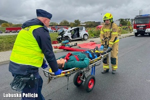 policjant i strażak udzielający pomocy poszkodowanemu