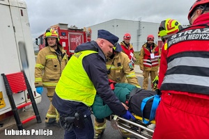 policjant i strażacy udzielający pomocy poszkodowanym