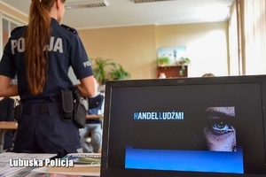 ekran laptopa i policjantka stojąca tyłem.