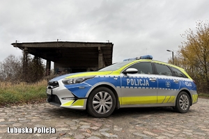 Oznakowany radiowóz policyjny na tle pustostanu.