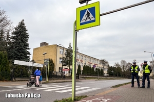 Policjanci stoją przy przejściu dla pieszych.