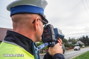 Policjant trzymający urządzenie służące do pomiaru prędkości