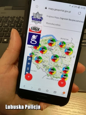 Telefon trzymany w ręku, na którym widoczna jest Krajowa Mapa Zagrożeń Bezpieczeństwa.