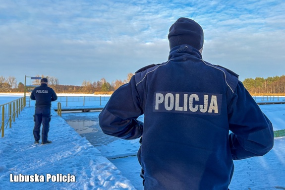 dwóch policjantów stojących na pomoście tyłem