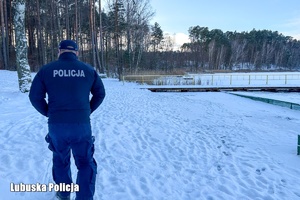 policjant idący przy zamarźniętym akwenie wodnym
