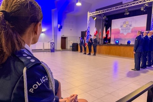 Ramie policjantki, w tle widać uroczystość.